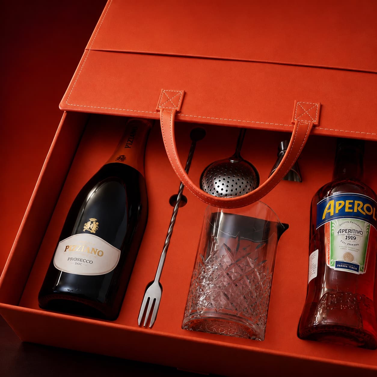 Açık haldeki turuncu Aperol PR kutusu: özel iç yerleşimde şişeler ve bar aksesuarları